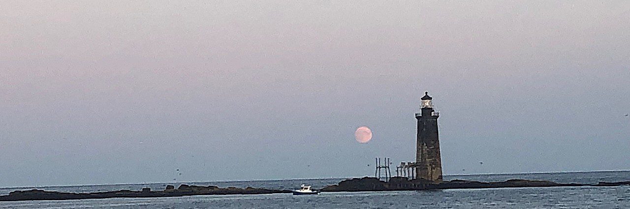 Moon rises behind Rame Island Ledge Lighthouse in Maine
