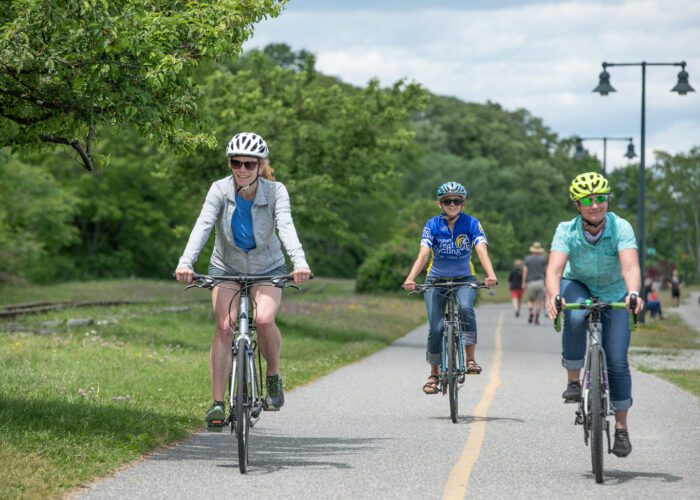 Three women bike on the Eastern Promenade Trail in Portland Maine